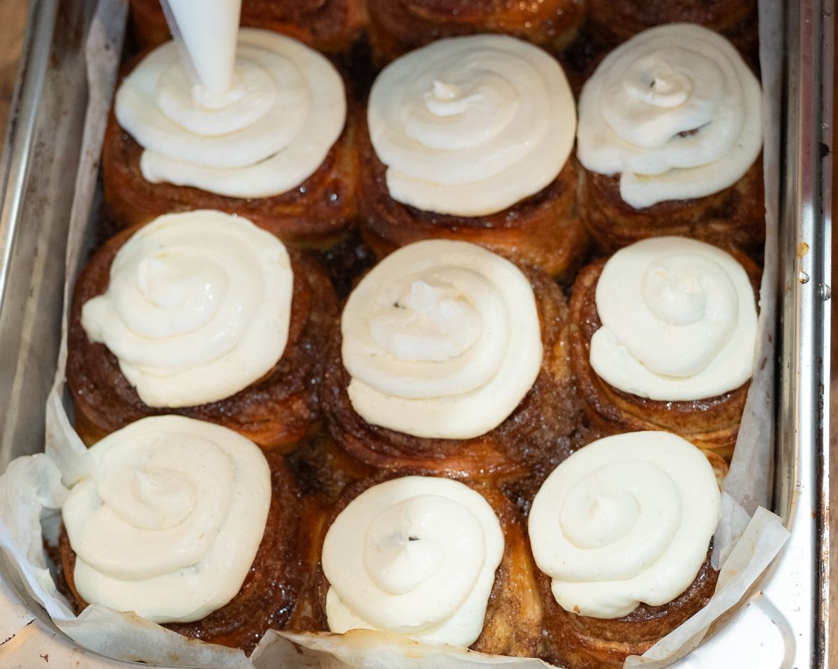 A tray of cinnamon rolls topped with cream